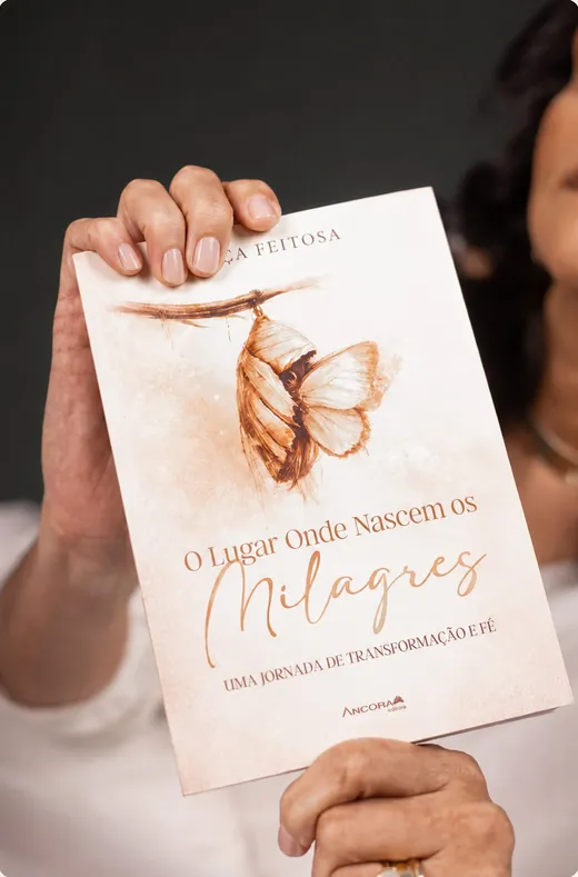 Mãos segurando o livro O lugar onde nascem os milagres, de Nilça Feitosa